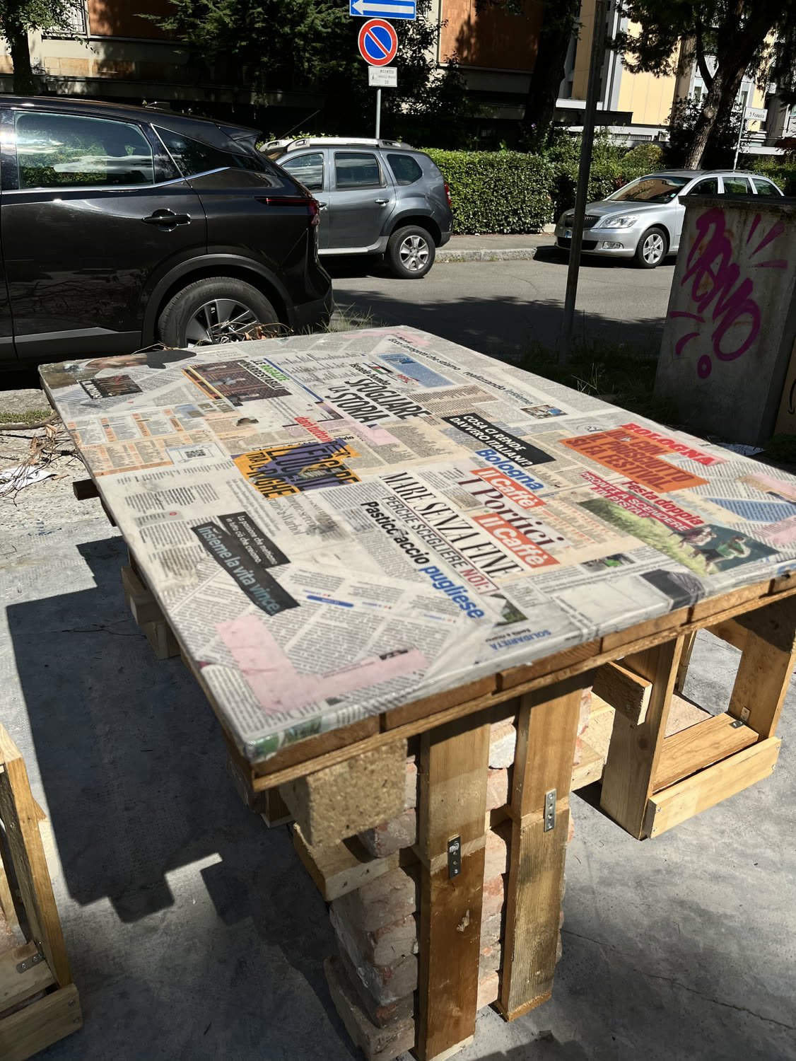 The tabletop, newspaper pages sealed under a clear surface