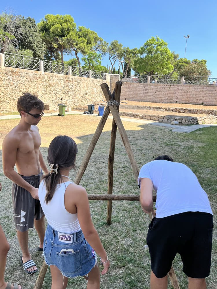 The first tripod standing, people steadying it